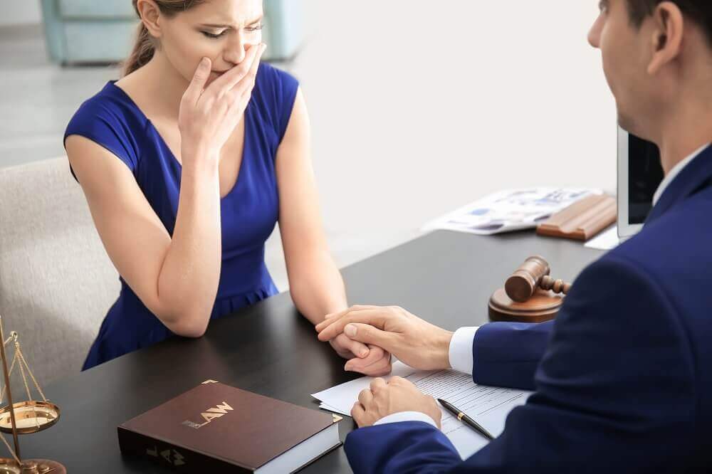 Crying widow consulting wrongful death attorney at law office.